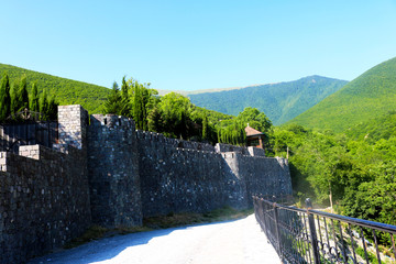Old stone fortress wall, stone road with an iron fence and peaks of green mountains in Sheki, Azerbaijan