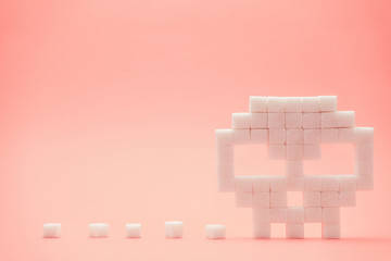 Skull with sugar cubes on a peach background. Concept sweet kill or unhealthy diet.
