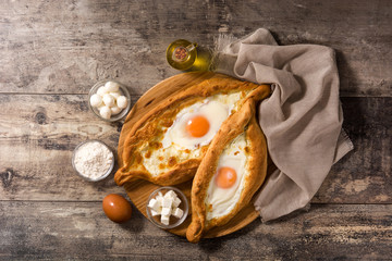 Traditional Adjarian Georgian khachapuri with cheese and egg on wooden table. Top view