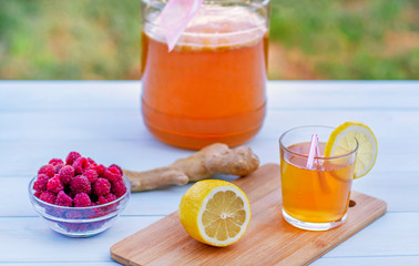 Glass jar with Kombucha, poured glass with Kombucha and raspberries in the summer garden.