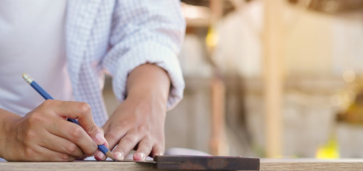 close up carpenter woman using ruler for measuring on timber at home concept	