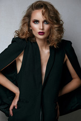 Fashion portrait of serious brunette woman with bright makeup wearing cape