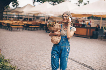 Carrying a healthy bag. Cropped image of beautiful young woman in apron holding paper shopping bag full of fresh vegetables