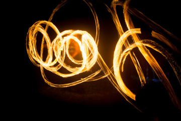 The artist shows a fire show at night spinning torches, circles of fire and loops