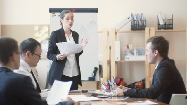 Office workers sit quietly and listen to remarks from the woman boss