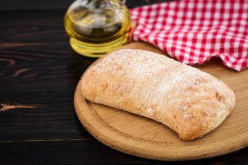 Loaf of ciabatta bread on a cutting board on the dark wooden table