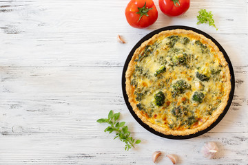 Traditional French Quiche with cheese, broccoli, spinach and chicken. Quiche lorraine. French cuisine. Top view. Light wooden background
