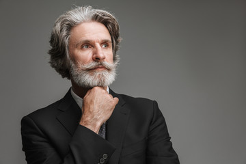 Image of handsome adult businessman wearing formal black suit looking aside at copyspace