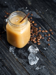 Jar of refreshing summer cold brewed coffee on a dark wooden table with crushed ice