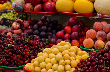 Containers with different ripe berries and fruit at market