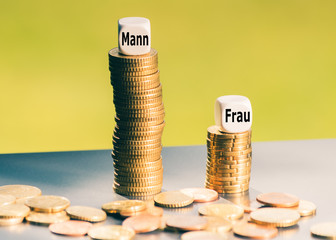 Unterschiedlich hohe Münzstapel symbolisieren die unterschiedliche Bezahlung von Männern und...