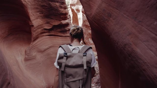 TRACKING Female hiking in slot canyon in Arizona, USA. Unusual colorful sandstone formations are popular destination for hikers. 4K UHD RAW graded footage