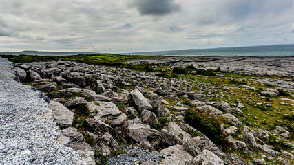 Irish landscape of limestone rocks and the sea in the background between Bothar nA hAillite and Fanore, geosite and geopark, Wild Atlantic Way, cloudy spring day in County Clare in Ireland