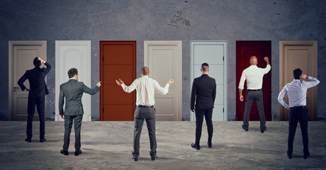 Business people looking to select the right door. Concept of confusion and competition