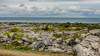 Fototapeta na wymiar Irish landscape of the sea and limestone rocks between Bothar nA hAillite and Fanore, geosites and geopark, Wild Atlantic Way, cloudy spring day in county Clare in Ireland