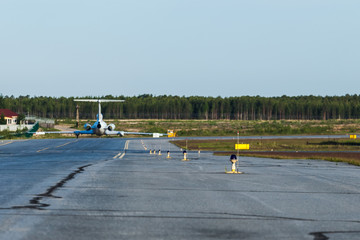 The airport blue lights on yellow line. Old aircraft on background.