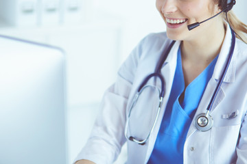 Doctor wearing headset sitting behind a desk with laptop