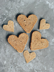 Rye bread in the shape of heart cut into slices on a gray background