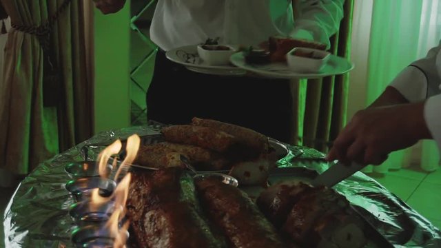 chef cuts roast meat near the fire