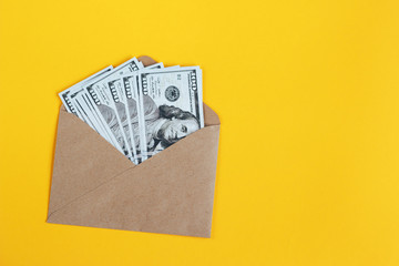 Paper envelope with money on a yellow background.