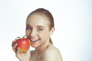 Portrait of happy smiling young beautiful woman eating red apple, over gray background