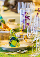 Wedding party dinner table setting with tableware and silverware and glasses set and Candlestick and flower in restaurant.