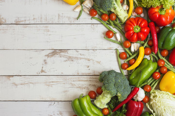 Horizontal background with a variety of seasonal vegetables. Green beans, cherry tomatoes, bell pepper, broccoli, lettuce and cabbage on wooden table