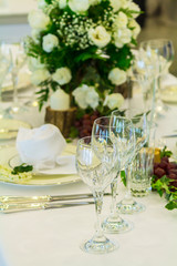 Thanksgiving party dinner table setting with tableware and silverware and glasses set and Candlestick and flower in restaurant.