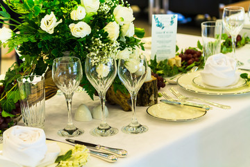 Christmas party dinner table setting with tableware and silverware and glasses set and Candlestick and flower in restaurant.