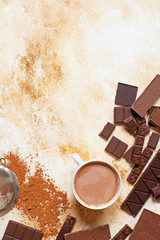 Cup of cocoa on a light marble background. Assortment of different types of chocolate and cocoa powder. Top view, flat lay. Space for text