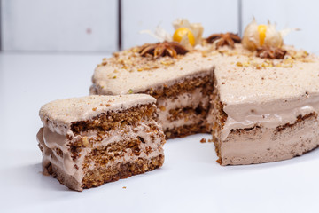  homemade, brown creamy cake with nuts and cream, on a light table