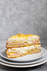 Sandwich with ham, cheese and bechamel sauce. A traditional french croque-monsieur sandwich served on a white plate. Gray background. Close-up. Front view. Space for text