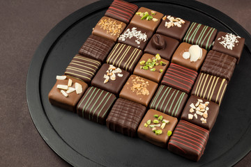 chocolates variety in black tray on brown background