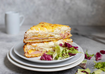 Sandwich with ham, cheese and bechamel sauce. A traditional french croque-monsieur sandwich served on a white plate. Gray background. Close-up. Front view. Space for text