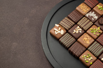 chocolates variety in black tray on brown background