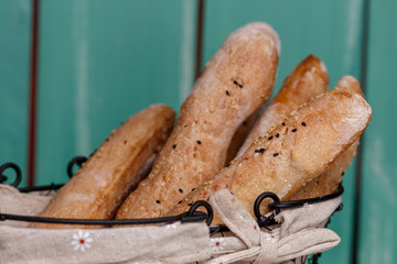 Homemade hide baguette with sesame and nuts. Bread of rye dough in a craft in a bread basket. Rye bread for dinner. Fresh fragrant delicious homemade pastries.