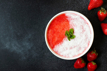 Strawberry smoothies or strawberries with ice in a white bowl. Served with coconut and mint. A...