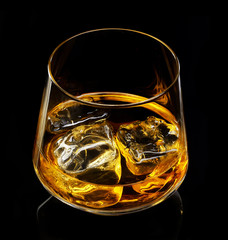 glass of whiskey with ice on a black background