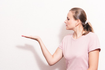 Fototapeta premium Woman surprise showing product .Beautiful girl pointing to the side . Presentation of your product. Expressive facial expressions