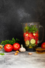 Traditional summer cold tomato soup gazpacho ingredients in a blender. Tomatoes, pepper, garlic, basil, parsley, olive oil and croutons. Mediterranean, Spanish cuisine. Black background. Copy space