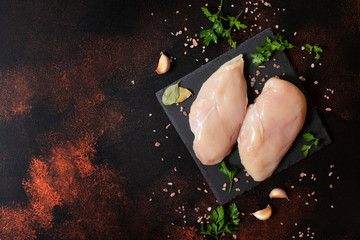 Two raw uncooked fresh chicken fillets on a black plate. Fresh poultry meat. Top view. Copy space