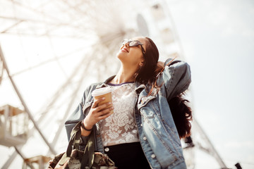 young stylish girl enjoys summer and vacation. Brunette in trendy sunglasses walks in the city