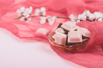 Pink chocolate bar and white flower on pink and red background. Ruby new chocolate. New pink sweet dessert