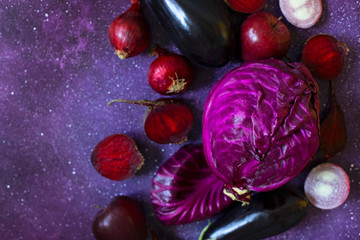 Purple fruits and vegetables on a purple background. Cabbage, apples, purple onions, beets, eggplant. Fresh farm vegetables and fruits in the same color range. Top view. Copy space