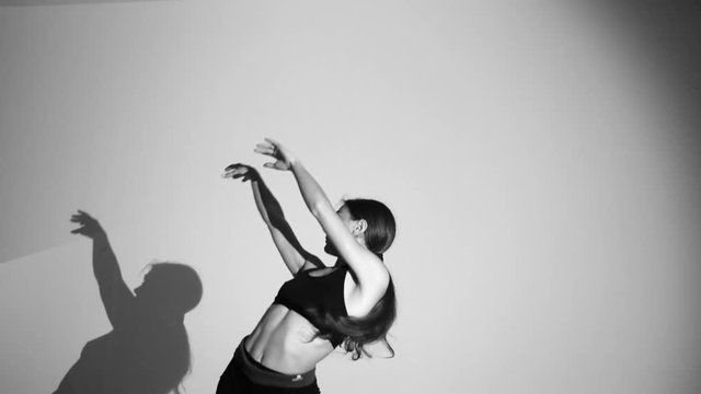 young ballerina dancing contemporary dance, isolated,the shadow repeats her movements,slow motion