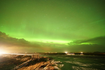 Strong Northern lights in Iceland on the road with forthcoming traffic