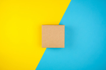 Fototapeta na wymiar square brown gift box on a yellow-blue background