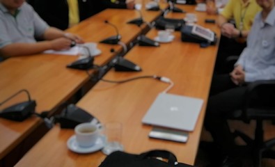 Businessmen are sitting at work meetings ..There are various equipment and coffee placed on the table...Blurred lens