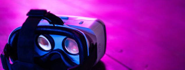 VR 3d 360 headset glasses goggles in futuristic purple neon light on table desk, virtual augmented...
