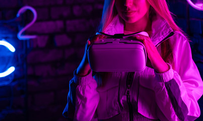 Young woman girl gamer hold 3d 360 vr headset ar innovative glasses play game in futuristic purple neon light, virtual augmented reality cyber space technology concept, close up view, copy space